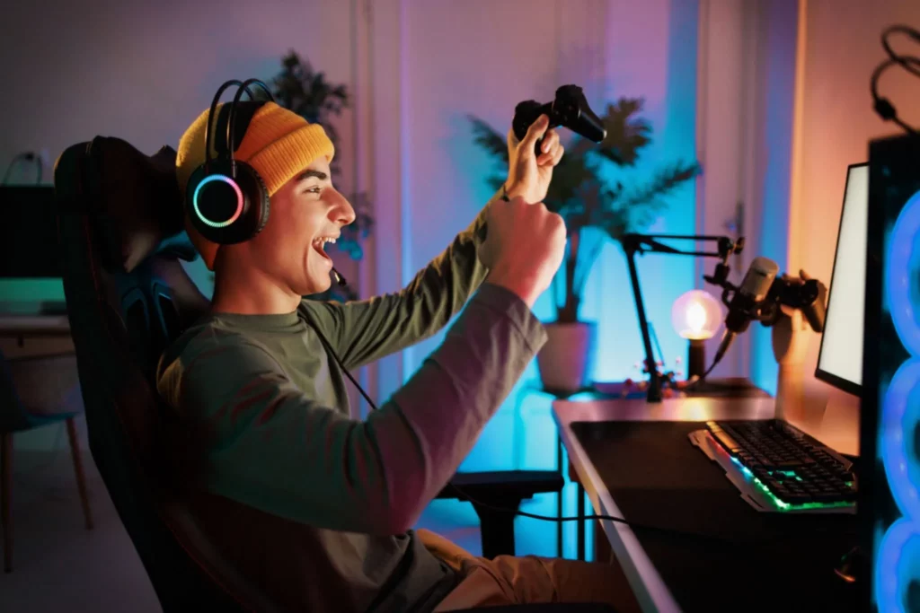 Young teenager plays the computer and celebrates victory in video game